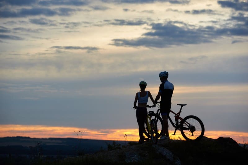 Rear View Of Two People With A Mountain Bike